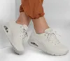 A person wearing beige Skechers Uno sneakers and brown pants. Voir les images du produit