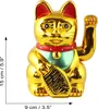 A golden Maneki Neko cat figurine with a red collar and a green bib, holding a golden object in its paw. Dimensions are indicated by measurement lines and text. Produktbild-Vorschau