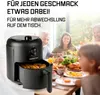 A family is enjoying a meal at a table, with an air fryer prominently displayed in the foreground. Produktbild-Vorschau