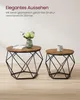 Two round coffee tables with geometric metal bases are shown. The larger table on the left has a book and a vase with flowers on it. The smaller table on the right has a mug on it. Podgląd zdjęcia produktu