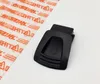 A black plastic part with an arrow symbol and ribbed texture is shown on a white background, next to a piece of clear plastic packaging with orange text. Produktbild-Vorschau