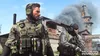 Two soldiers in tactical gear stand in front of a burning building. Produktbild-Vorschau
