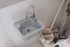 A utility sink with a faucet running, next to cleaning supplies. Anteprima dell’immagine prodotto