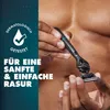 A person is holding a razor against a backdrop of water droplets and skin. Produktbild-Vorschau