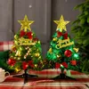 Two small, decorated Christmas trees with LED lights and ornaments, placed on a table with a checkered tablecloth. Náhled obrázku produktu