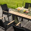 An outdoor dining set with a table and chairs on a wooden deck, set in a grassy area. Produktbild-Vorschau