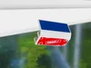 A close-up of a white clip with a blue top and red sides featuring a repeating pattern of the 'tesa' logo. Produktbild-Vorschau