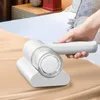 A hand is using a white handheld vacuum cleaner on a tan surface, likely a bed or sofa. Náhľad obrázku produktu