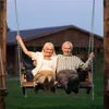 An elderly couple sitting on a swing in front of a house. Náhled obrázku produktu