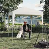 A man sits under a white canopy tent next to a guitar, with a lake and mountains in the background and a campfire in the foreground. Produktbild-Vorschau