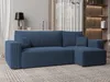 A blue sectional sofa is shown in a living room setting with a rug, curtains, and shelving in the background. Produktbild-Vorschau