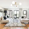 A modern living room with a sectional sofa, coffee table, and a ceiling light fixture. Produktbild-Vorschau