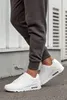 A person wearing dark grey sweatpants and white sneakers. Produktbild-Vorschau