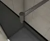 A close-up view of a corner of a modern shower enclosure, showing the glass panel, a metal support bar, and the shower tray. Produktbild-Vorschau