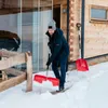 A man is shoveling snow in front of a wooden house. Náhled obrázku produktu