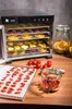 A food dehydrator with multiple trays filled with dried fruits and vegetables, placed on a wooden table. Podgląd zdjęcia produktu
