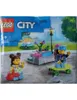 The image shows the packaging of a LEGO City playset, featuring two minifigures and a small park scene. Podgląd zdjęcia produktu