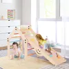 Two young children playing on a wooden climbing triangle with a slide in a bright, airy room. Produktbild-Vorschau