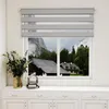 A window with zebra blinds and a view of houses and mountains. Voir les images du produit
