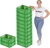 A woman stands next to a tall stack of green crates, leaning on them. Produktbild-Vorschau
