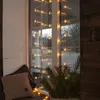 A window sill decorated with star-shaped string lights, a pillow, and a pine branch. Podgląd zdjęcia produktu