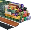 A collection of HEM incense boxes stacked in a pyramid shape, with a wooden incense holder and black incense sticks in the foreground. Podgląd zdjęcia produktu