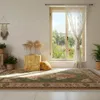 A bright, airy room with a window overlooking a garden, featuring a rug, plants, and decorative items. Produktbild-Vorschau