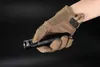 A hand wearing a tan tactical glove holds a black flashlight. Produktbild-Vorschau