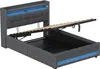 A grey upholstered bed frame with the mattress support lifted to reveal the storage compartment underneath. Blue LED lighting is visible along the headboard and the base of the frame. Produktbild-Vorschau