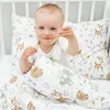 A baby sitting in a crib with bedding featuring animal prints. Produktbild-Vorschau