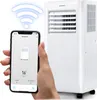 A hand holding a smartphone displaying a portable AC control app, with a white portable air conditioner unit in the background. Podgląd zdjęcia produktu