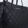 A close-up shot of a black quilted tote bag with a gold Valentino logo. Produktbild-Vorschau