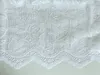 A close-up view of white lace fabric with a floral pattern. Produktbild-Vorschau