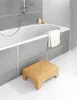 A bathroom scene with a bathtub, showerhead, and a wooden step stool. Produktbild-Vorschau