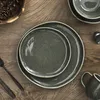 A top-down view of plates and cutlery on a wooden table, with pinecones in a bowl. Voir les images du produit