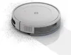 A white robot vacuum cleaner is shown on a white background, cleaning up scattered debris. Voir les images du produit