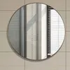 A round mirror with a gold frame is mounted on a tiled wall. Produktbild-Vorschau