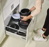 A person is organizing pots and pans in a kitchen drawer. Produktbild-Vorschau