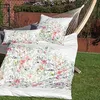 A floral patterned duvet cover and pillow set laid out in a hammock in a garden setting. Produktbild-Vorschau