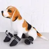 A stuffed dog wearing dog boots, sitting in front of a white brick wall. Náhled obrázku produktu