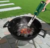 A person is using a green electric hot air blower to ignite charcoal in a black barbecue grill outdoors. Produktbild-Vorschau
