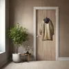 A coat hangs on a hook on a wooden door in a hallway. There is a potted plant and a small table with flowers next to the door. The floor is made of light-colored wood. Produktbild-Vorschau