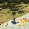 A portable fan is placed on a picnic blanket with some snacks and fruit, outdoors on a grassy area with dappled sunlight. Anteprima dell’immagine prodotto