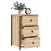 A wooden nightstand with three drawers and black metal legs, placed on a white background. A small alarm clock and a vase of greenery are on top of the nightstand. Náhled obrázku produktu