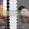 A person sleeping in bed, with a city skyline and a window blind in the foreground. Produktbild-Vorschau
