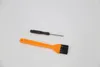 A black screwdriver and an orange brush are laid out on a white background. Náhled obrázku produktu