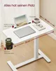 A white adjustable height side table with a laptop, tablet, cup, and glasses on it, with dimensions indicated. Produktbild-Vorschau