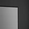 A close-up view of the corner of a mirror with a black frame against a textured dark gray wall. Produktbild-Vorschau