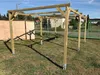 A wooden carport structure is set up on a grassy area with a shed in the background. Produktbild-Vorschau