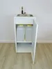 A white mobile sink unit with a stainless steel basin and faucet, standing on a light wooden floor against a white wall. The cabinet below the sink is open, revealing two large translucent water containers. Podgląd zdjęcia produktu